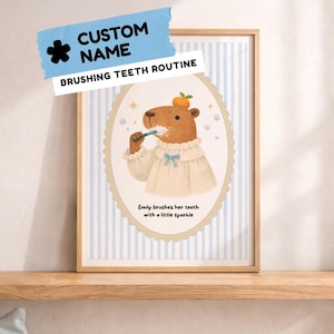 Puede incluir: Una impresión enmarcada con un capibara de dibujos animados cepillándose los dientes, con un vestido y una fruta en la cabeza. La impresión tiene un fondo a rayas azules y blancas e incluye el texto "Custom Name" y "Brushing Teeth Routine".