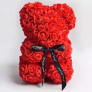 以下が含まれることがあります： 小さなバラで作られた赤いバラのクマ。クマは、白い文字で「Just for you」と書かれた黒いリボンで結ばれています。装飾品です。