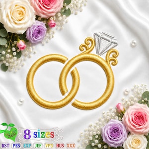 Puede incluir: Un diseño de bordado que presenta dos anillos dorados entrelazados con un engaste de diamante plateado, rodeado de rosas blancas, rosas y moradas y flores de aliento de bebé sobre un fondo de tela de satén blanco con texto que indica 8 tamaños.