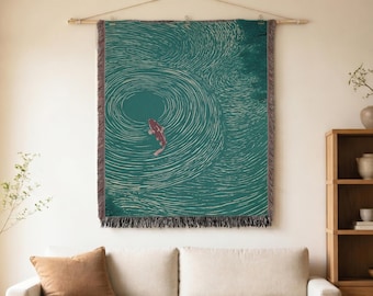 May include: A rectangular woven wall tapestry featuring a deep teal background with white concentric circular ripples and a single red koi fish swimming in the centre. The textile has a fringed bottom edge and hangs from a wooden rod.