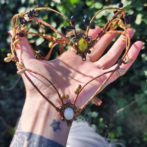 Puede incluir: Una diadema delicada, de color marr&oacute;n, con forma de rama, con detalles dorados y negros. La diadema presenta dos piedras preciosas ovaladas, una amarilla y otra blanca.