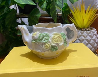 Vintage petit chandelier en forme de théière en céramique avec fleurs jaune. Théière blanche. Article neuf dans son papier d’emballage.