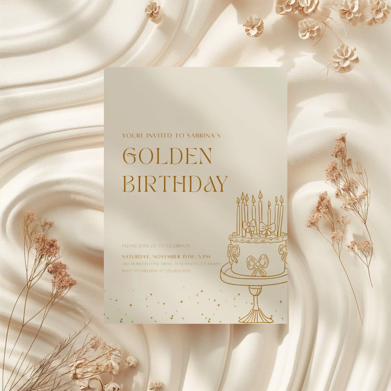 May include: A cream-colored invitation with gold text that reads "Golden Birthday." The invitation features a cake illustration with lit candles and decorative elements. The background is a soft, textured fabric.