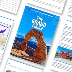 May include: A travel guide titled "The Grand Circle" with a blue cover featuring an arch rock formation. The guide is surrounded by other pages with maps and text, promoting exploration of Utah and Arizona.