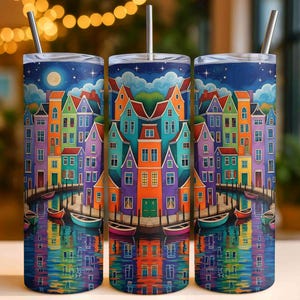 May include: Three stainless steel tumblers with a colorful illustration of a European canal scene. The design features vibrant houses in various colors, boats, and reflections in the water under a starry night sky. Each tumbler has a silver straw.