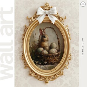 May include: An oval-shaped wall art piece featuring a painting of a bunny in a basket with eggs. The painting is set in a gold ornate frame and topped with a white bow. The background is a floral wallpaper.
