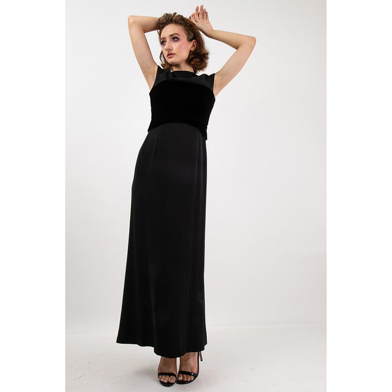 May include: A black sleeveless maxi dress with a velvet bodice. The dress has a simple, elegant design and is perfect for a formal occasion.