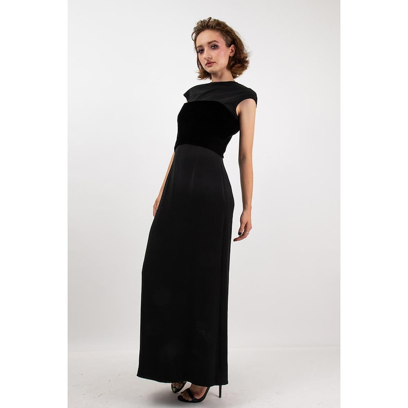 May include: A black maxi dress with a velvet band around the waist. The dress has a sleeveless design and a scoop neck.