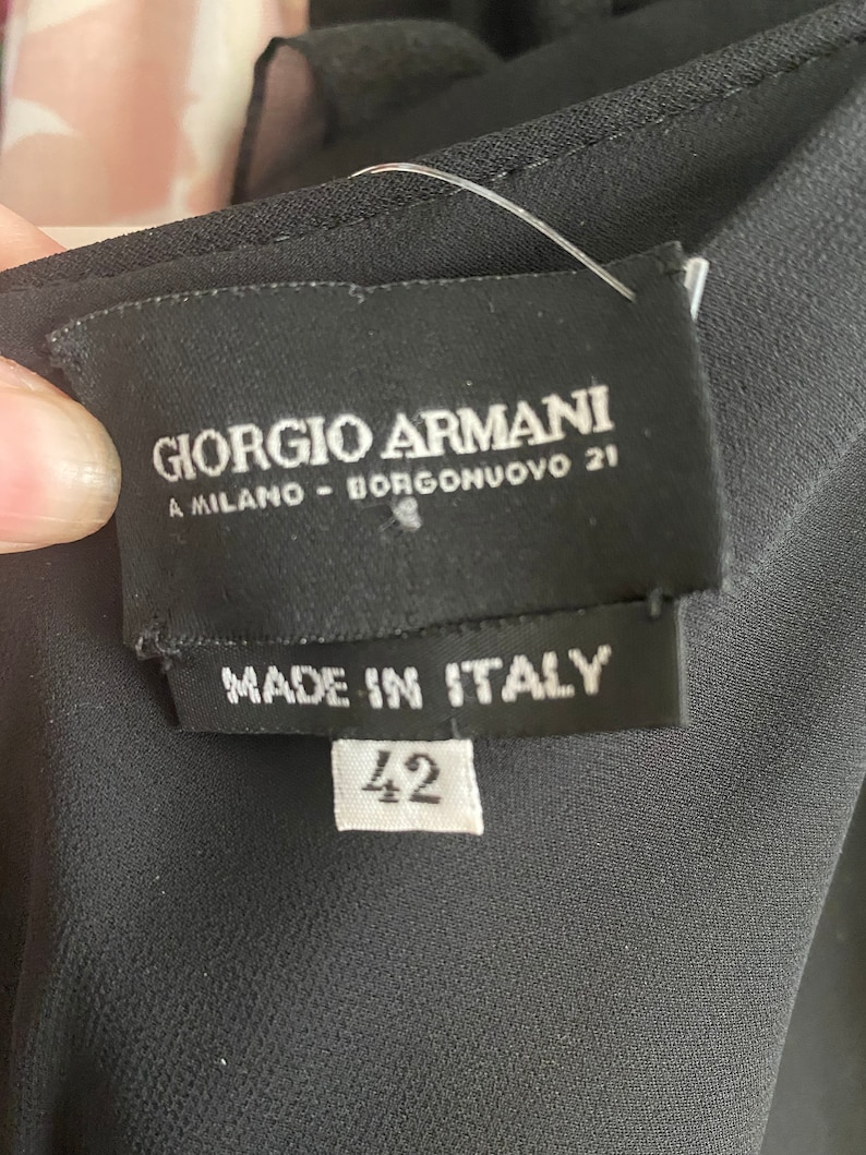 May include: Black label with white text that reads "Giorgio Armani A Milano - Borgonuvo 21" and "Made in Italy". A white tag with the number "42" is attached to the label.