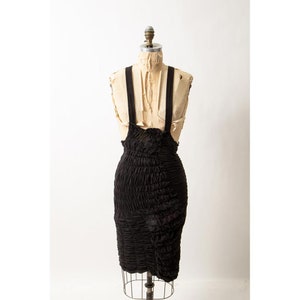 Puede incluir: Un vestido negro sin mangas, fruncido, con tirantes finos en un maniquí vintage.