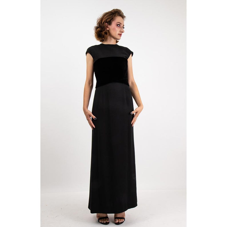 May include: A black maxi dress with a velvet band across the bust. The dress has short sleeves and a simple, elegant design.