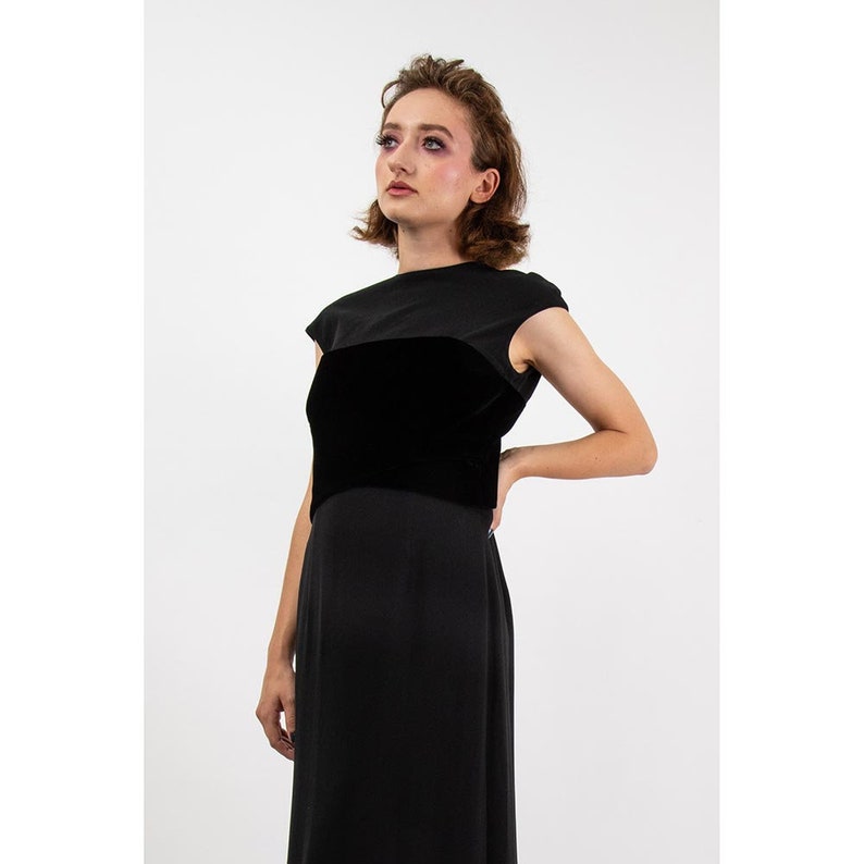 May include: A black sleeveless dress with a velvet bodice. The dress has a simple, elegant design.