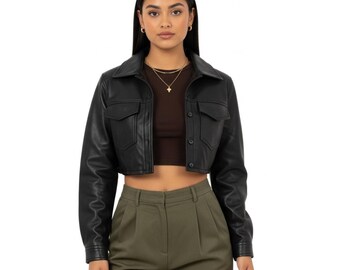 May include: Black cropped jacket with a collared neckline and two front pockets. The jacket is made of a smooth material and has long sleeves. The model is wearing a brown top and olive green pants.