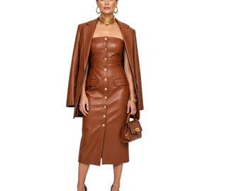 May include: A woman wearing a brown leather dress with gold buttons, a matching blazer, and a small handbag. She is also wearing gold jewelry, including a choker, earrings, and a bracelet. The dress is knee-length and has a fitted silhouette.
