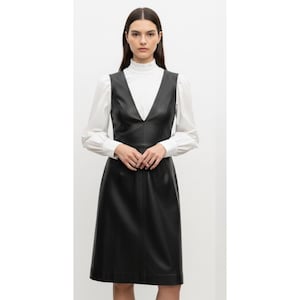 leather pinny dress A modern essential: The Leather Pinafore Dress. Crafted in supple black leather with gold hardware, designed to bring structure and versatility to your fall uniform