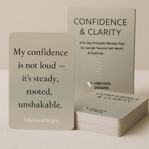 Puede incluir: Un juego de tarjetas y una caja de color gris claro. Las tarjetas y la caja muestran el texto "CONFIDENCE & CLARITY" y "Vibe Vista Designs". Una tarjeta muestra el texto: "My confidence is not loud - it's steady, rooted, unshakable."