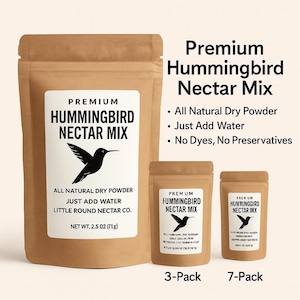 May include: Three brown paper pouches of hummingbird nectar mix. The largest pouch has a white label with the text "Premium Hummingbird Nectar Mix" and a black hummingbird graphic. The smaller pouches are labeled "3-Pack" and "7-Pack".