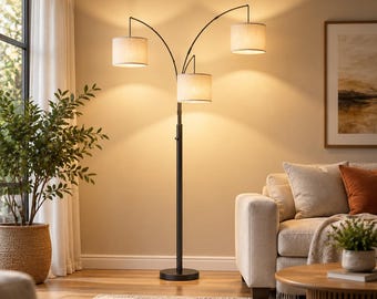 May include: A black metal floor lamp with three arched arms, each supporting a cylindrical beige fabric shade. The lamp features a central pole base and emits a warm, soft glow, illuminating the surrounding space in a living room.