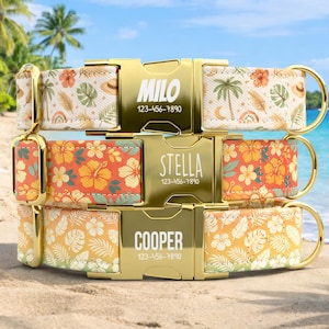May include: Three personalized dog collars with gold-colored buckles. The top collar has a white background with a tropical pattern and the name "Milo" and a phone number. The middle collar has an orange floral pattern and the name "Stella". The bottom collar has a yellow floral pattern and the name "Cooper".