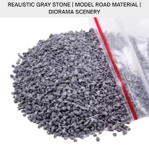 Könnte beinhalten: Ein Haufen kleiner, grauer Steine, wahrscheinlich für Modellstraßenmaterial oder Dioramenlandschaften. Die Steine haben eine einheitliche graue Farbe und scheinen unterschiedliche Größen zu haben. Der Text oben lautet: REALISTIC GRAY STONE | MODEL ROAD MATERIAL | DIORAMA SCENERY.