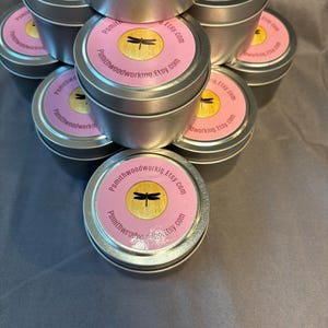 Può includere: Una pila di piccole lattine di metallo argentato con etichette rosa e oro. Le etichette presentano un disegno di libellula e il testo "Psmithwoodworking.Etsy.com". Le lattine sono cilindriche.