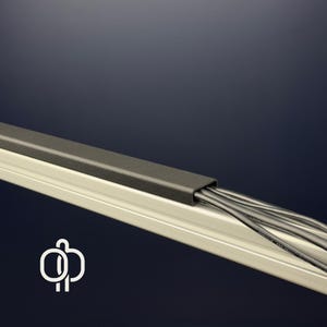 Könnte beinhalten: Ein Kabelmanagementsystem mit einem dunkelgrauen Deckel und einer hellgrauen Basis. Mehrere schwarze Kabel sind im Inneren sichtbar. Das System dient dazu, Kabel zu organisieren und zu verbergen, wodurch ein sauberes und professionelles Aussehen entsteht.