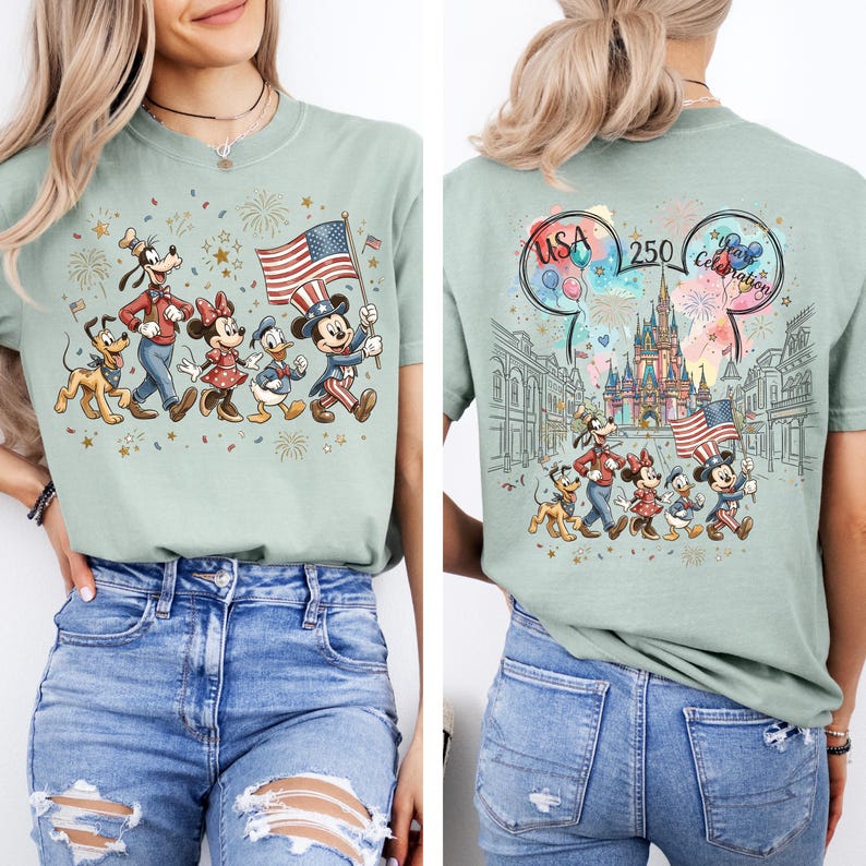 May include: A sage green t-shirt featuring a graphic of Mickey Mouse, Minnie Mouse, Donald Duck, Goofy, and Pluto wearing patriotic clothing and holding an American flag. The back design includes a castle, fireworks, and the text USA 250 Years Celebration.