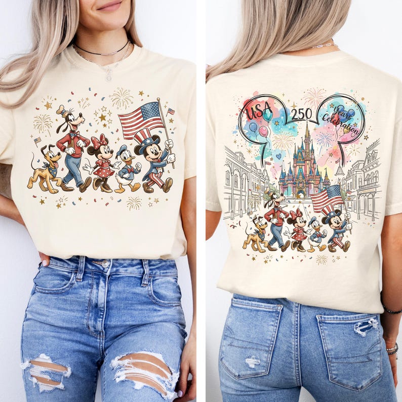 May include: A cream-colored t-shirt featuring a graphic of Pluto, Goofy, Minnie Mouse, Donald Duck, and Mickey Mouse holding an American flag. The back design includes a castle, fireworks, and the text USA 250 Year Celebration in Mickey ears.