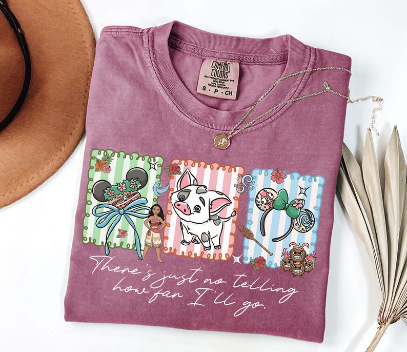 May include: A mauve short-sleeve t-shirt featuring a graphic print of Moana, Pua the pig, and themed mouse ears within three rectangular frames. The text "There's just no telling how far I'll go" is printed in white script below the illustrations.