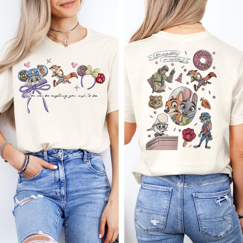 May include: A cream-colored t-shirt featuring Zootopia characters and icons. The front displays mouse ears and the text "You can be anything you wish to be." The back shows a collage of characters, a badge, a donut, and a carrot graphic.