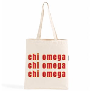 Op de afbeelding: Een natuurkleurige canvas draagtas met twee lange schouderbanden. De voorzijde van de tas toont de tekst "chi omega" gedrukt in een vetgedrukt, rood lettertype met een gele omlijning, herhaald in drie horizontale rijen in het midden.
