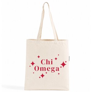 Peut inclure: Un sac fourre-tout en toile de couleur naturelle avec le texte rouge Chi Omega imprimé au centre. Le motif est agrémenté de plusieurs étoiles rouges à quatre branches de tailles variées dispersées autour du lettrage sur le devant du sac.