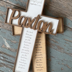 Peut inclure: Une croix en bois avec le nom "Paxton" grav&eacute; dessus. La croix est d&eacute;cor&eacute;e d'un fond blanc et du texte "Baptis&eacute; le 11 septembre 2022". La croix comprend &eacute;galement un verset de la Bible, Nombres 6&nbsp;:&nbsp;24-26, qui se lit comme suit&nbsp;: &laquo;&nbsp;Que le Seigneur te b&eacute;nisse et te garde&nbsp;; que le Seigneur fasse briller sa face sur toi et te fasse gr&acirc;ce&nbsp;; que le Seigneur tourne son visage vers toi et te donne la paix.&nbsp;&raquo;