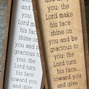 Peut inclure: Deux marque-pages en bois avec un fond blanc et brun. Les marque-pages pr&eacute;sentent le texte "Le Seigneur te b&eacute;nisse et te garde : Que le Seigneur fasse briller sa face sur toi et te soit favorable ; que le Seigneur tourne sa face vers toi et te donne la paix. Nombres 6:24-26"