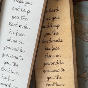 Peut inclure: Une pancarte en bois avec le texte "The Lord bless you and keep you: the Lord make his face shine on you and be gracious to you: the Lord turn his face toward you and give you peace." La pancarte est de couleur brun clair et a un cadre brun fonc&eacute;.