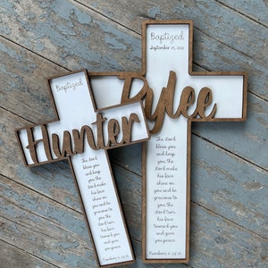 Peut inclure: Deux croix en bois avec les noms Hunter et Rylie dessus. Les croix sont d&eacute;cor&eacute;es du texte "Baptized" et de la date "September 25, 2022". Les croix comprennent &eacute;galement un verset biblique de Nombres 6:24-26.