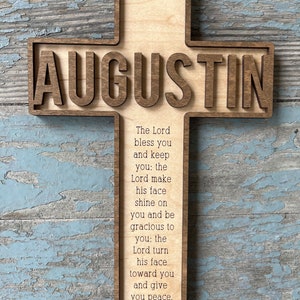 Peut inclure: Une croix en bois avec le nom "AUGUSTIN" grav&eacute; dessus. La croix est d&eacute;cor&eacute;e du texte "Baptized September 11, 2022" et d'un verset biblique : "L'&Eacute;ternel te b&eacute;nisse et te garde : l'&Eacute;ternel fasse briller sa face sur toi et te fasse gr&acirc;ce : l'&Eacute;ternel tourne sa face vers toi et te donne la paix. Nombres 6:24-26"
