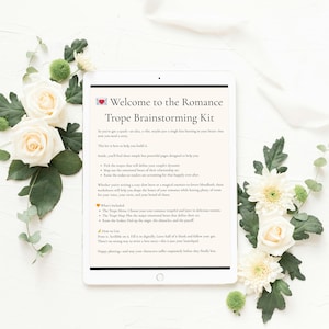 以下が含まれることがあります： 「Welcome to the Romance Trope Brainstorming Kit」のテキストが表示されたタブレットが、白いバラ、緑、白いリボンで囲まれています。タブレットの画面には、ロマンス小説の書き方に関するテキストが表示されています。全体的な美しさは柔らかく、女性的です。