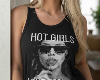 Może przedstawiać: Czarny top bez rękawów z napisem "HOT GIRLS LOVE TECHNO" i grafiką kobiety w okularach przeciwsłonecznych liżącej lizaka. Top jest w stylu prążkowanym.