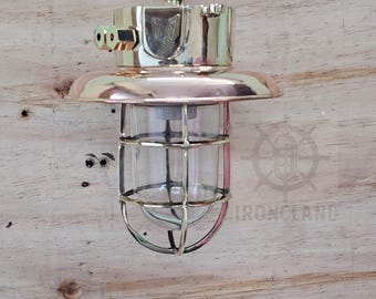 Lámpara colgante de jaula náutica de latón con pantalla de cobre.