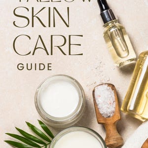 以下が含まれることがあります： 「Tallow Skin Care Guide」のテキストが入ったスキンケア製品のフラットレイ。クリームのジャー、キャンドル、ドロッパーボトル、木製の塩スクープが含まれています。緑の葉と白いタオルも写っています。