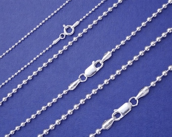 May include: Several silver ball chain necklaces with different thicknesses and lengths are displayed against a blue background. Each necklace has a clasp for secure fastening. The chains are made of small, round, metallic beads.