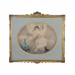 May include: An antique framed print featuring an oval image of three figures in white robes. The print is set against a light blue background within a gold-colored ornate frame. A blue vase sits on a small table in the foreground.