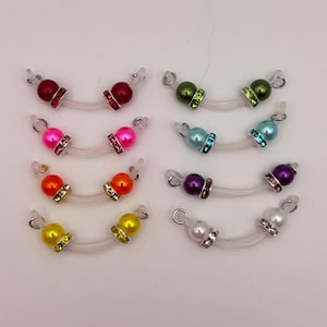 May include: A collection of eyeglass chains with colorful, decorative beads. The beads come in various colors, including red, pink, orange, yellow, green, blue, purple, and white. Each chain has a clear, flexible loop for attaching to glasses.