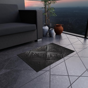 May include: Black rectangular outdoor rug with an embossed geometric pattern. The rug is on a tiled patio, near a dark grey sofa and decorative pots. The rug's design features squares and intricate floral details.