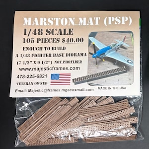 Op de afbeelding: Een pakket Marston Mat (PSP) modelbouwkit onderdelen. De kit is 1/48 schaal en bevat 105 onderdelen. De verpakking bevat een afbeelding van een modelvliegtuig en de tekst "ENOUGH TO BUILD A 1/48 FIGHTER BASE DIORAMA (19 cm X 24 cm) NOT PROVIDED".