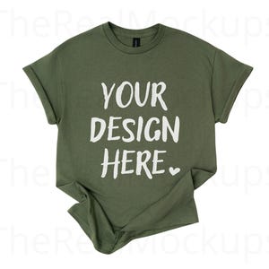 以下が含まれることがあります： オリーブグリーンのTシャツ、袖はロールアップされています。「YOUR DESIGN HERE」の文字が白でプリントされ、小さなハートマークが付いています。カスタムデザイン用のモックアップTシャツです。