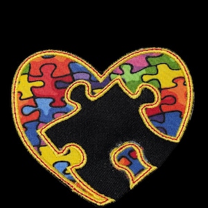 May include: A heart-shaped patch with a puzzle design. The heart is outlined in yellow and filled with colorful puzzle pieces in red, blue, green, and yellow. A missing puzzle piece is visible in the center, against a black background.
