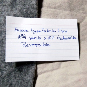 May include: A white note card with blue ink that reads "Suede type fabric lined 3 3/4 yards x 54 inches wide Reversible".