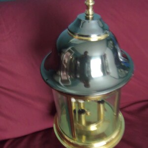 May include: A gold and silver clock with a glass dome and a pendulum. The clock has a decorative top with a pointed finial.